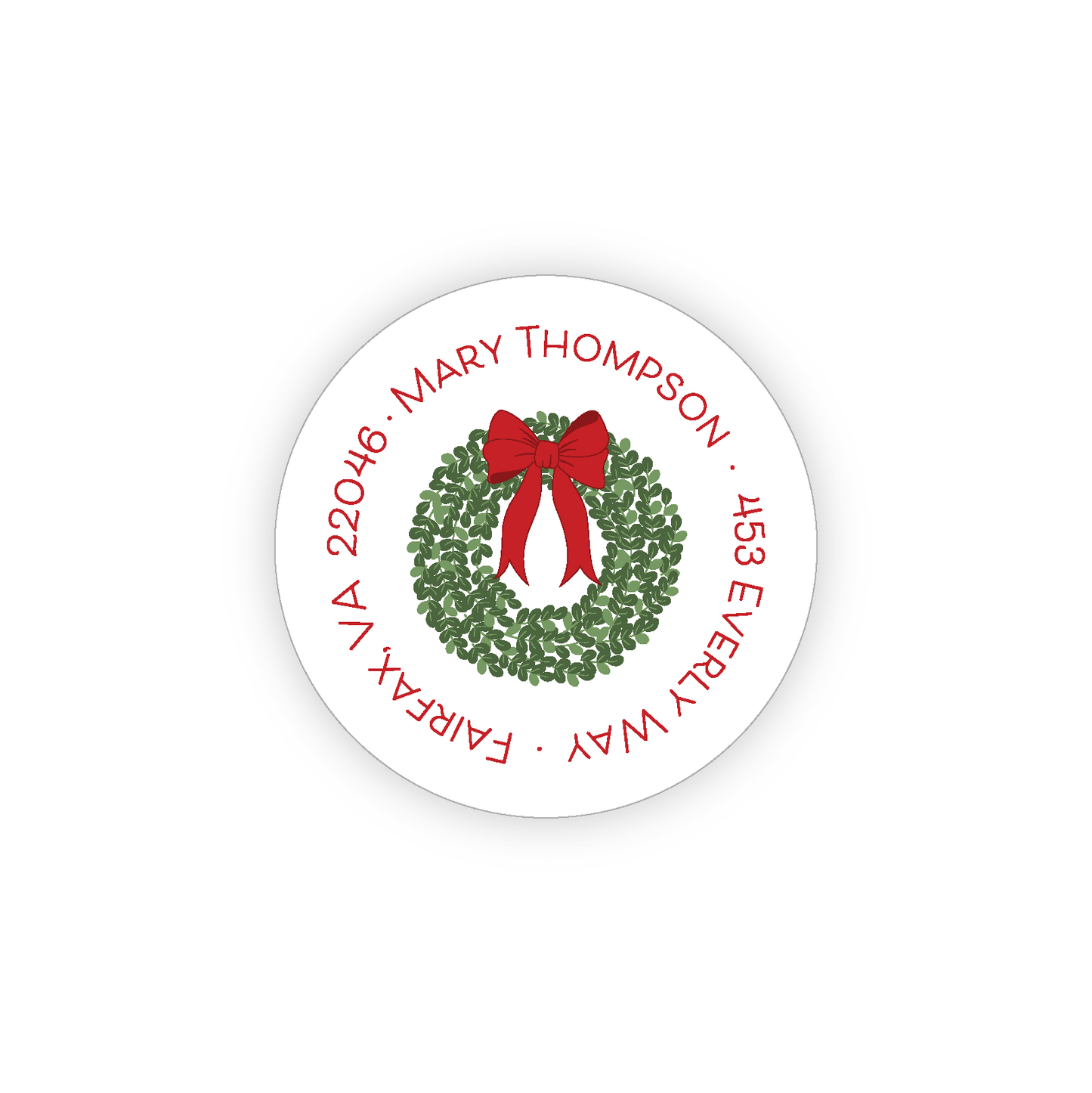 Green boxwood wreath with a red bow on a round address label. The address is in a circle around the edge of the label.