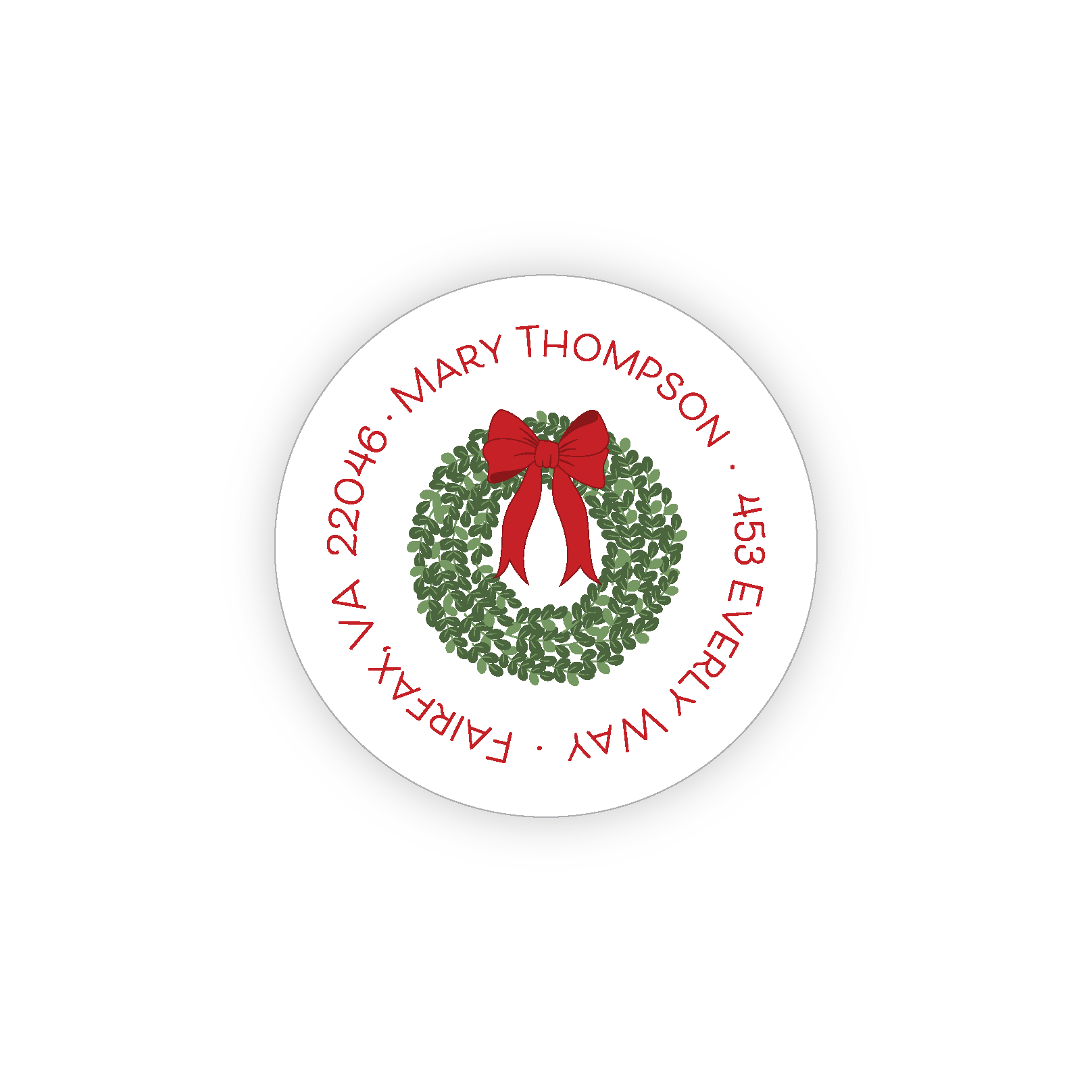 Green boxwood wreath with a red bow on a round address label.  The address is in a circle around the edge of the label. 